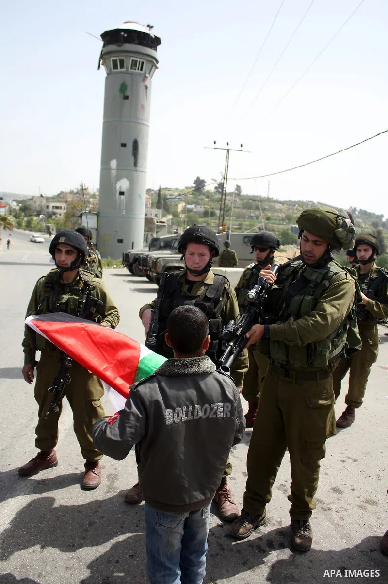 A Palestinian boy argues with Israeli soldiers during a protest by foreign, Israeli and Palestinian demonstrators against the controversial Israeli separation barrier, in the Palestinian village of Beit Omar, near the We...