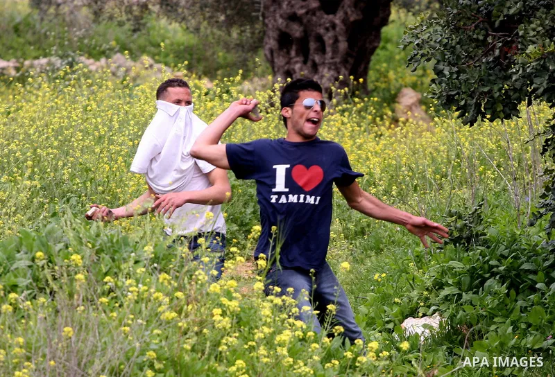 Palestinian youths hurl stones towards Israeli soldiers during a demonstration against the expansion of the nearby Jewish settlement of Halamish in the West Bank village of Nabi Saleh near Ramallah, Saturday, April 2, 20...