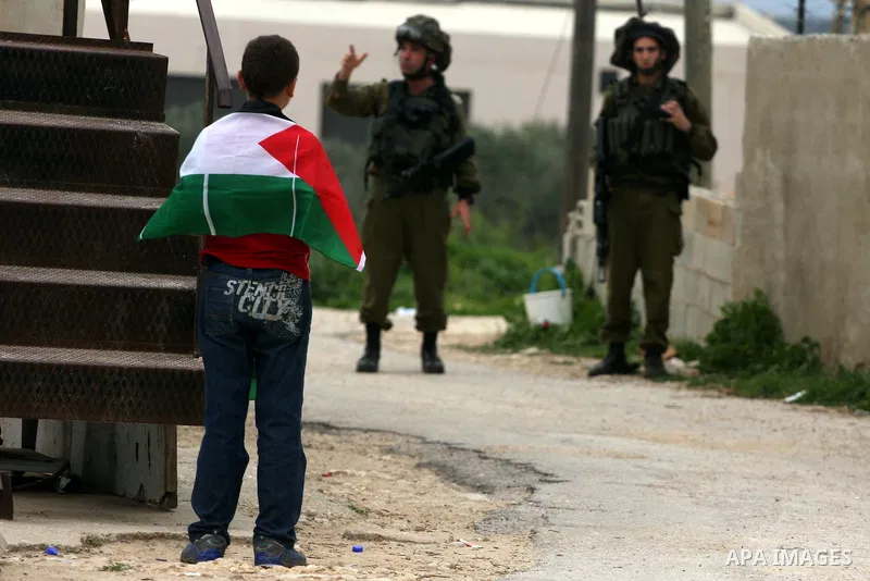 Palestinian youths hurl stones towards Israeli soldiers during a demonstration against the expansion of the nearby Jewish settlement of Halamish in the West Bank village of Nabi Saleh near Ramallah, Saturday, April 2, 20...