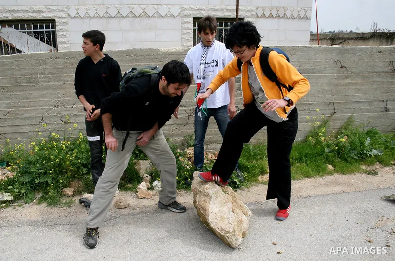 Protestors lay a bloc in the road during a demonstration against the expansion of the nearby Jewish settlement of Halamish in the West Bank village of Nabi Saleh near Ramallah, Saturday, April 2, 2011. Photo by Issam Rim...