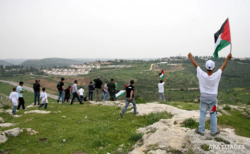 Palestinian youths hurl stones towards Israeli soldiers during a demonstration against the expansion of the nearby Jewish settlement of Halamish in the West Bank village of Nabi Saleh near Ramallah, Saturday, April 2, 20...