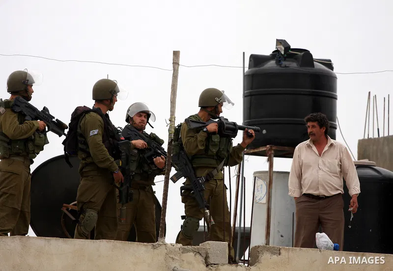 Israeli border police officers argue with a Palestinian man on the roof of a house during clashes at a protest against the expansion of the nearby Jewish settlement of Halamish in the West Bank village of Nabi Saleh near...