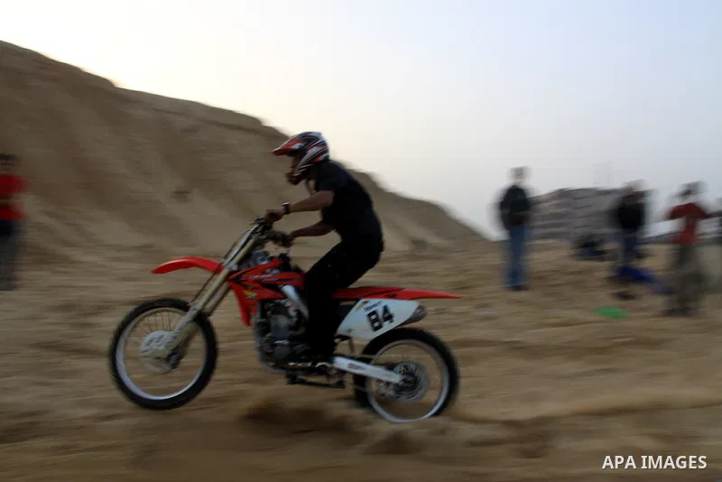 A Palestinian man rides his motorcycle on sand dunes during the weekly sport event in the Gaza Strip town of al-Zahra, south of Gaza City, on April 1,2011. Palestinian youths use the dunes for riding their motorcycles, h...