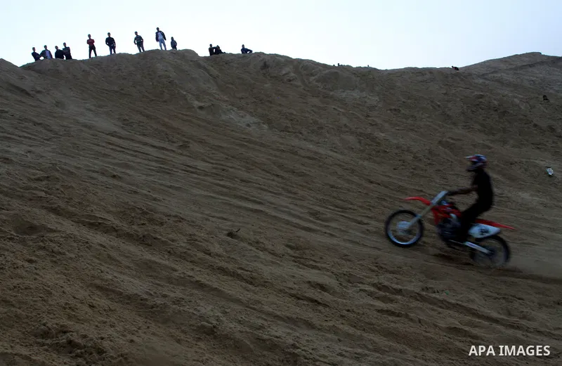 A Palestinian man rides his motorcycle on sand dunes during the weekly sport event in the Gaza Strip town of al-Zahra, south of Gaza City, on April 1,2011. Palestinian youths use the dunes for riding their motorcycles, h...