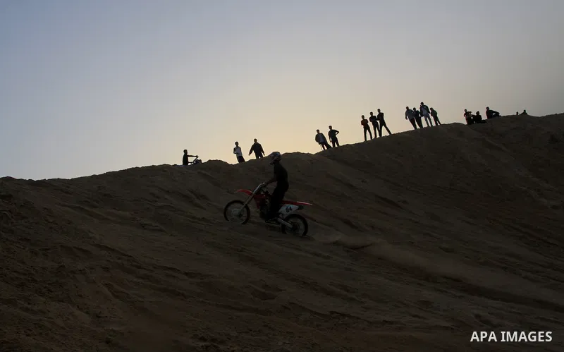 A Palestinian man rides his motorcycle on sand dunes during the weekly sport event in the Gaza Strip town of al-Zahra, south of Gaza City, on April 1,2011. Palestinian youths use the dunes for riding their motorcycles, h...