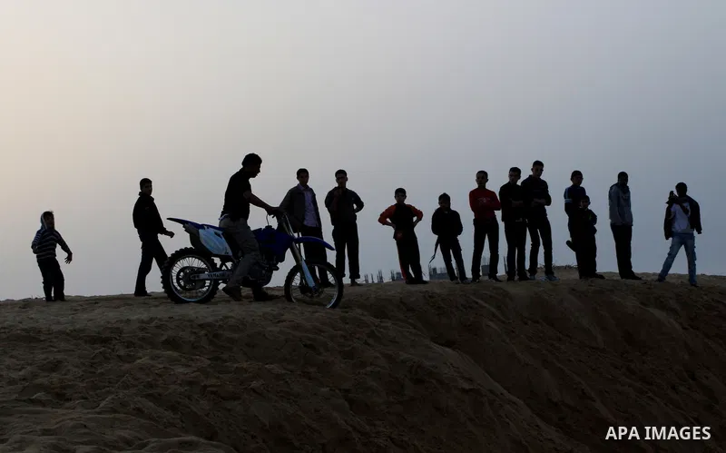 A Palestinian man rides his motorcycle on sand dunes during the weekly sport event in the Gaza Strip town of al-Zahra, south of Gaza City, on April 1,2011. Palestinian youths use the dunes for riding their motorcycles, h...