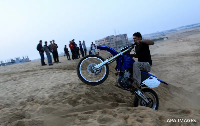 A Palestinian man rides his motorcycle on sand dunes during the weekly sport event in the Gaza Strip town of al-Zahra, south of Gaza City, on April 1,2011. Palestinian youths use the dunes for riding their motorcycles, h...