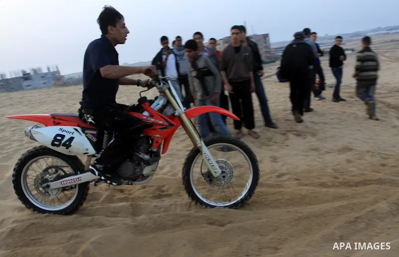 A Palestinian man rides his motorcycle on sand dunes during the weekly sport event in the Gaza Strip town of al-Zahra, south of Gaza City, on April 1,2011. Palestinian youths use the dunes for riding their motorcycles, h...