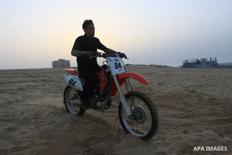 A Palestinian man rides his motorcycle on sand dunes during the weekly sport event in the Gaza Strip town of al-Zahra, south of Gaza City, on April 1,2011. Palestinian youths use the dunes for riding their motorcycles, h...