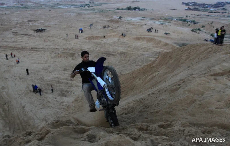 A Palestinian man rides his motorcycle on sand dunes during the weekly sport event in the Gaza Strip town of al-Zahra, south of Gaza City, on April 1,2011. Palestinian youths use the dunes for riding their motorcycles, h...