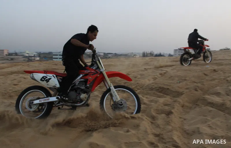 A Palestinian man rides his motorcycle on sand dunes during the weekly sport event in the Gaza Strip town of al-Zahra, south of Gaza City, on April 1,2011. Palestinian youths use the dunes for riding their motorcycles, h...