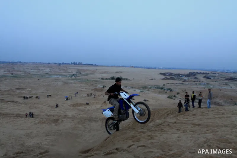 A Palestinian man rides his motorcycle on sand dunes during the weekly sport event in the Gaza Strip town of al-Zahra, south of Gaza City, on April 1,2011. Palestinian youths use the dunes for riding their motorcycles, h...