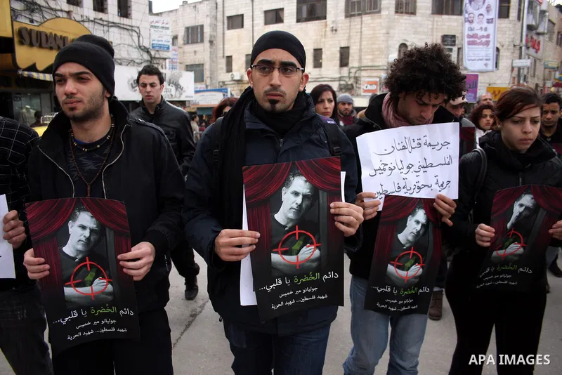 Palestinians hold signs and posters depicting Arab-Israeli actor and director Juliano Mer Khamis during a rally in the West Bank city of Ramallah on April 5, 2011. A senior Palestinian security official said on Tuesday p...