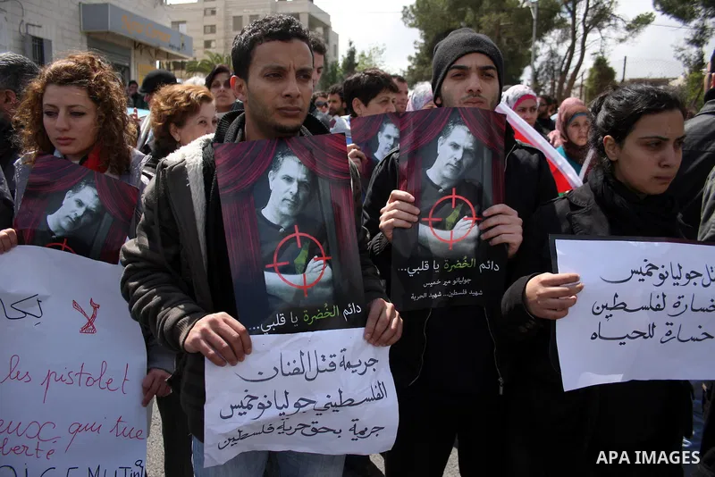 Palestinians hold signs and posters depicting Arab-Israeli actor and director Juliano Mer Khamis during a rally in the West Bank city of Ramallah on April 5, 2011. A senior Palestinian security official said on Tuesday p...