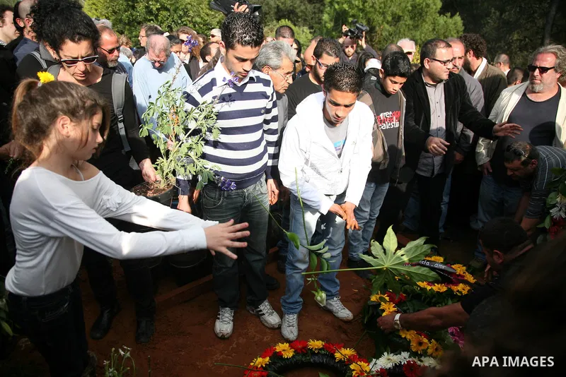 Milay, daughter of Arab-Israeli actor and director Juliano Mer Khamis, holds a flower as she stands next to her father's coffin during the funeral procession in Haifa, northern Israel, Wednesday, April 6, 2011. Mer-Khami...
