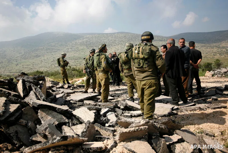 An Israeli earth-mover destroys a main road in Aqaba near the West Bank village of Tubas in the northern Jenin region on April 7, 2011 as the military used bulldozers to destroy Palestinian houses in another farming vill...