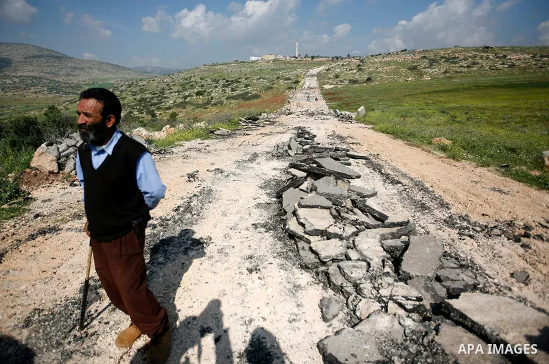 An Israeli earth-mover destroys a main road in Aqaba near the West Bank village of Tubas in the northern Jenin region on April 7, 2011 as the military used bulldozers to destroy Palestinian houses in another farming vill...