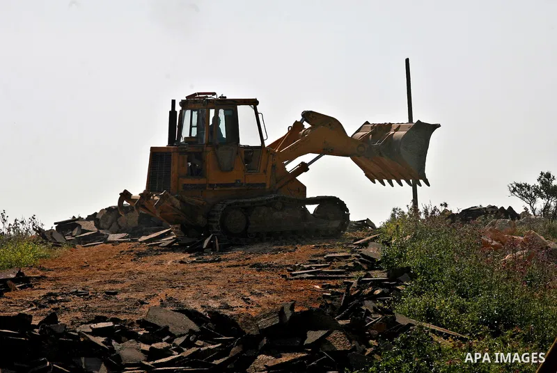 An Israeli earth-mover destroys a main road in Aqaba near the West Bank village of Tubas in the northern Jenin region on April 7, 2011 as the military used bulldozers to destroy Palestinian houses in another farming vill...