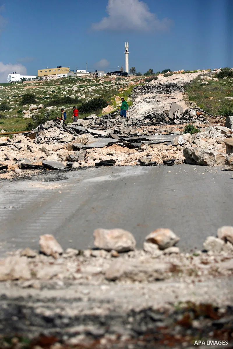 An Israeli earth-mover destroys a main road in Aqaba near the West Bank village of Tubas in the northern Jenin region on April 7, 2011 as the military used bulldozers to destroy Palestinian houses in another farming vill...