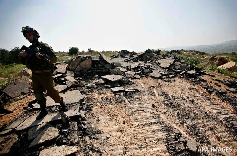 An Israeli earth-mover destroys a main road in Aqaba near the West Bank village of Tubas in the northern Jenin region on April 7, 2011 as the military used bulldozers to destroy Palestinian houses in another farming vill...