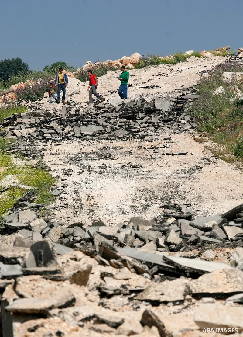 An Israeli earth-mover destroys a main road in Aqaba near the West Bank village of Tubas in the northern Jenin region on April 7, 2011 as the military used bulldozers to destroy Palestinian houses in another farming vill...