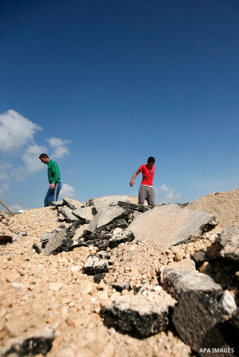 An Israeli earth-mover destroys a main road in Aqaba near the West Bank village of Tubas in the northern Jenin region on April 7, 2011 as the military used bulldozers to destroy Palestinian houses in another farming vill...