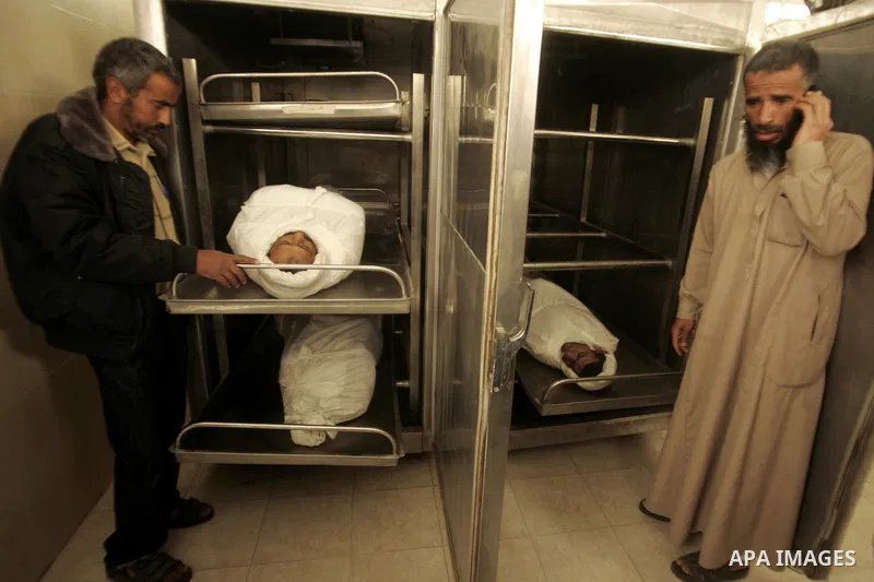 Palestinians stand next to the bodies of three Palestinians prior to their funerals at al-Najar hospital mortuary room in the southern Gaza Strip town of Rafah on April 8, 2011. The three were killed the day before in a...