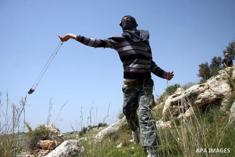 A Palestinian protestor hurls stones at Israeli soldiers during the weekly demonstration against Israel's separation barrier in the West Bank village of Nilin, near Ramallah, Friday, April 8, 2011. Israel says the barrie...