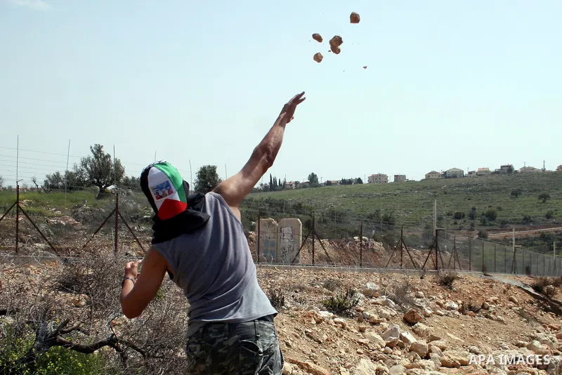 A Palestinian protestor hurls stones at Israeli soldiers during the weekly demonstration against Israel's separation barrier in the West Bank village of Nilin, near Ramallah, Friday, April 8, 2011. Israel says the barrie...
