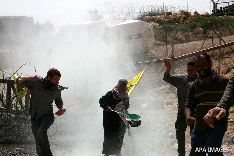Palestinian protestors run for cover colored water during the weekly demonstration against Israel's separation barrier in the West Bank village of Bilin, near Ramallah, Friday, April 8, 2011. Israel says the barrier is n...
