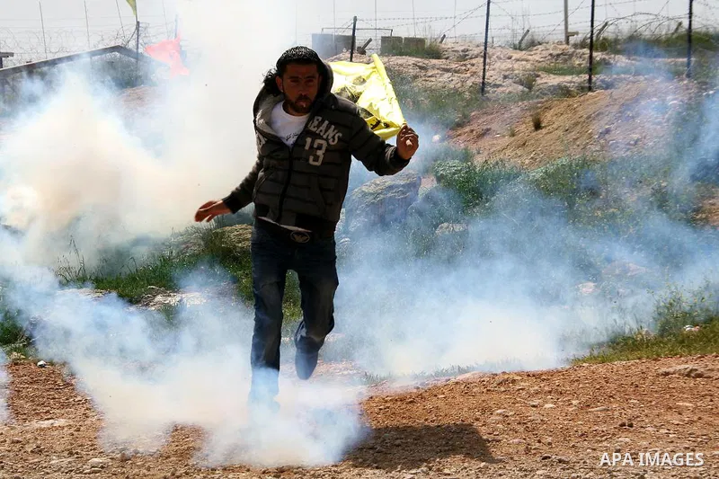 Palestinian protestors run for cover from tear gas fired by Israeli soldiers during the weekly demonstration against Israel's separation barrier in the West Bank village of Bilin, near Ramallah, Friday, April 8, 2011. Is...