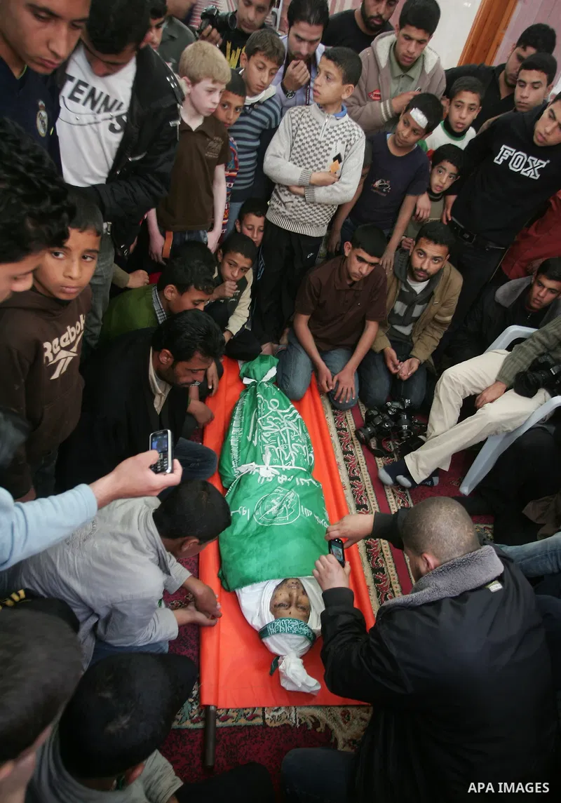 Palestinians sit next to the body of the boy Mahmoud Al-Jaroh who was killed in an Israeli air Strike on Friday, during his funeral at a mosque in Gaza City April 9, 2011. Militant group Hamas said on Saturday it would e...