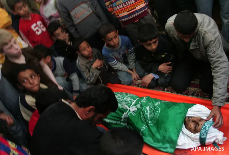Palestinians sit next to the body of the boy Mahmoud Al-Jaroh who was killed in an Israeli air Strike on Friday, during his funeral at a mosque in Gaza City April 9, 2011. Militant group Hamas said on Saturday it would e...