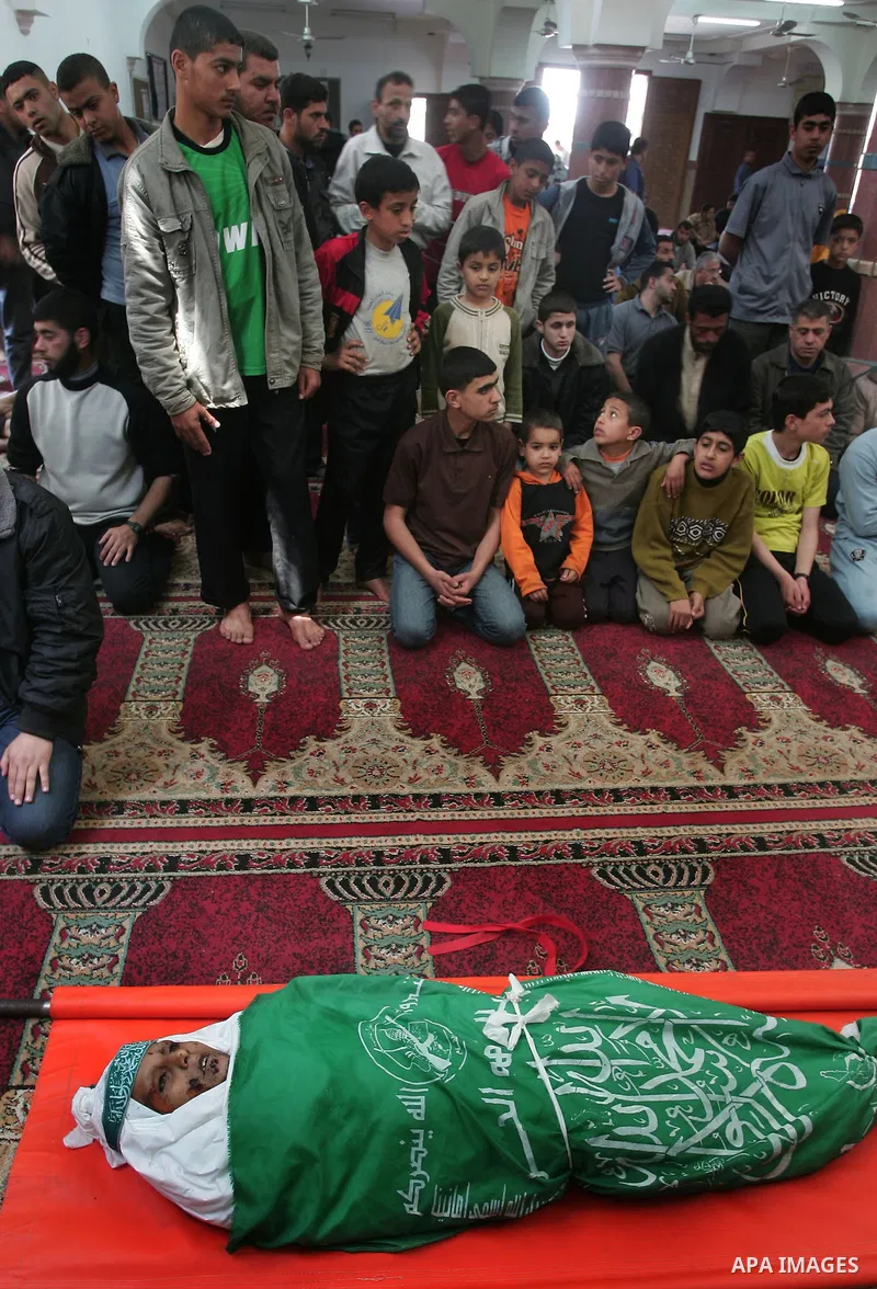 Palestinians sit next to the body of the boy Mahmoud Al-Jaroh who was killed in an Israeli air Strike on Friday, during his funeral at a mosque in Gaza City April 9, 2011. Militant group Hamas said on Saturday it would e...