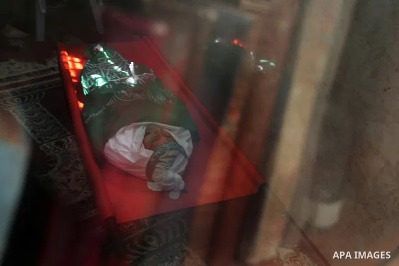 Palestinians are reflected on a glass rack as they sit next to the body of the boy Mahmoud Al-Jaroh who was killed in an Israeli air Strike on Friday, during his funeral at a mosque in Gaza City April 9, 2011. Militant g...