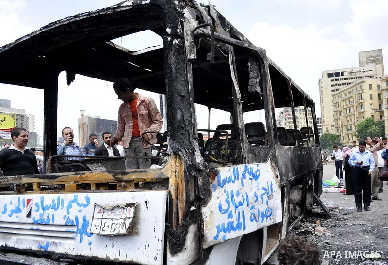 Egyptians gather past a burnt truck at Tahrir Square in Cairo on April 9, 2011 following clashes in which two people were killed and at least 18 wounded when Egyptian military police stormed the capital's iconic square t...