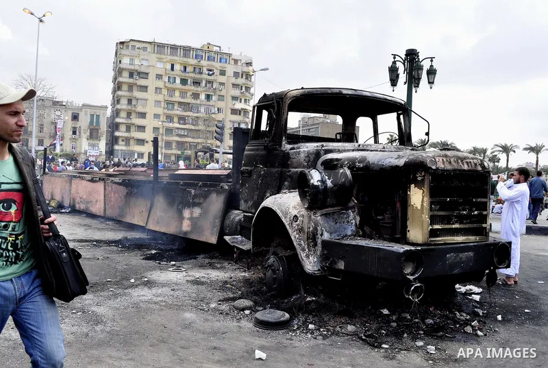 Egyptians gather past a burnt truck at Tahrir Square in Cairo on April 9, 2011 following clashes in which two people were killed and at least 18 wounded when Egyptian military police stormed the capital's iconic square t...