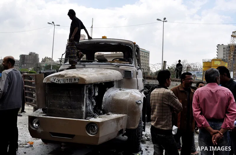Egyptians gather past a burnt truck at Tahrir Square in Cairo on April 9, 2011 following clashes in which two people were killed and at least 18 wounded when Egyptian military police stormed the capital's iconic square t...