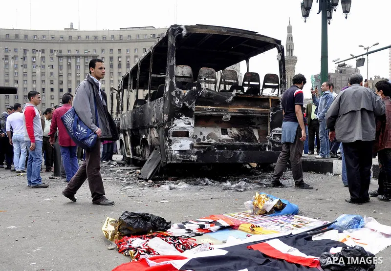Egyptians gather past a burnt truck at Tahrir Square in Cairo on April 9, 2011 following clashes in which two people were killed and at least 18 wounded when Egyptian military police stormed the capital's iconic square t...