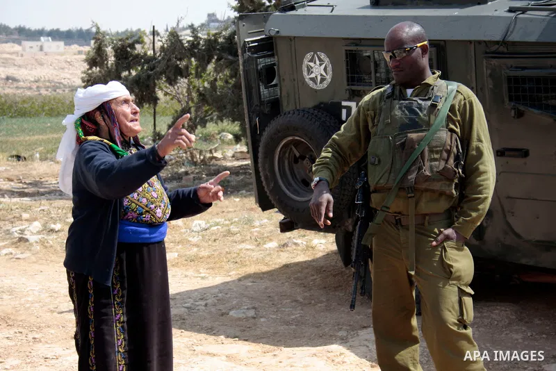 A Palestinian woman quarrels with Israeli soldiers during a protest rally against Jewish settlers in the West Bank village of Yatta, south of Hebron, on April 09,2011.Photo by Najeh Hahlamoun