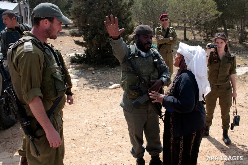 A Palestinian woman quarrels with Israeli soldiers during a protest rally against Jewish settlers in the West Bank village of Yatta, south of Hebron, on April 09,2011.Photo by Najeh Hahlamoun