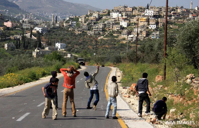 Palestinian youths throw stones at Israeli soldiers during which clashes erupted following an Israeli army operation in the village of Awarta near the West Bank city of Nablus, Sunday, April 10, 2011. The Israeli army of...