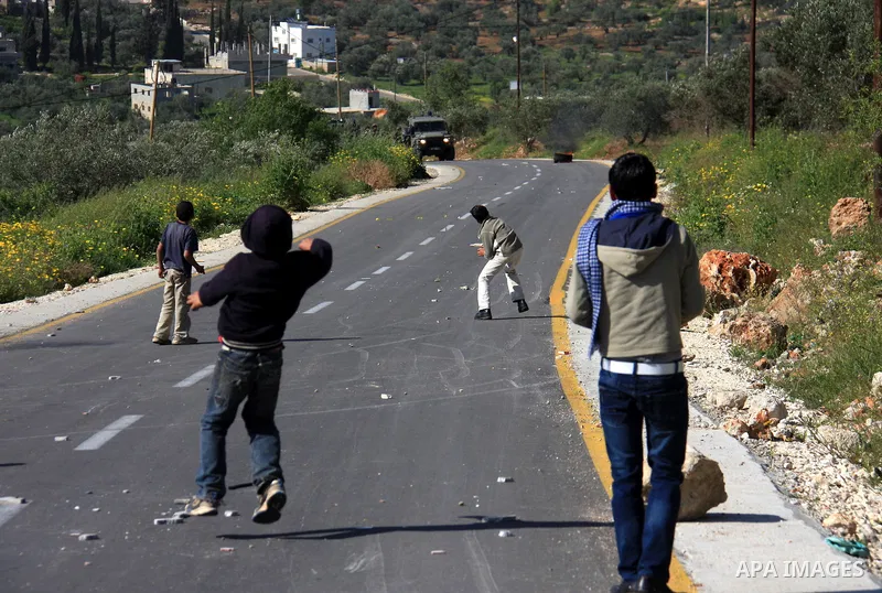 Palestinian youths throw stones at Israeli soldiers during which clashes erupted following an Israeli army operation in the village of Awarta near the West Bank city of Nablus, Sunday, April 10, 2011. The Israeli army of...