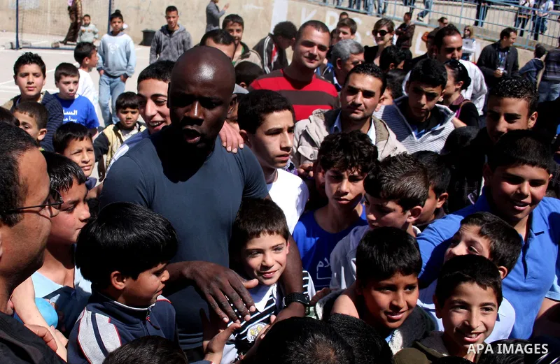 Former French soccer player Lilian Thuram visits a school in the West bank refugee camp of Kalandia, on 11 April 2011. Thuram is visiting the Palestinian territory in support of the education programme funded by France t...