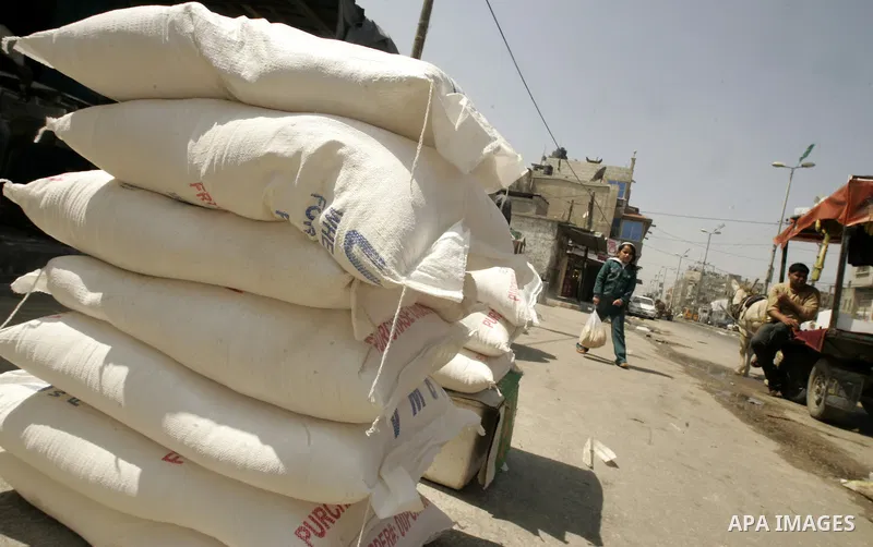 Palestinians walk past sacks of flour in front a shop in Rafah, southern Gaza Strip on April 11,2011. A shortage in basic goods in Gaza during the first quarter of 2011 due to continued Israeli preventing to enter most o...
