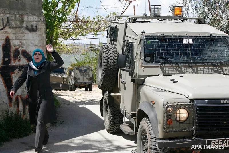 A Palestinian woman reacts as Israeli troops carry out a search operation in the West Bank village of Awarta on April 12, 2011 as the northern West Bank village has been the centre of a massive army hunt for the killers...