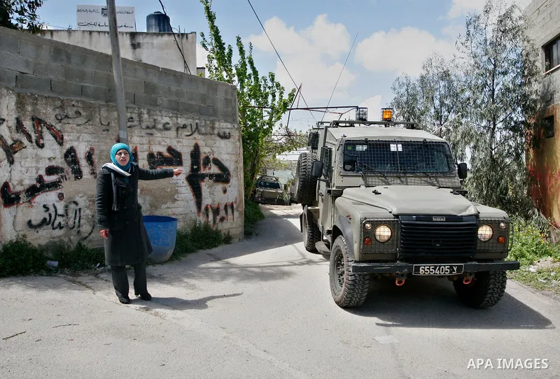 A Palestinian woman reacts as Israeli troops carry out a search operation in the West Bank village of Awarta on April 12, 2011 as the northern West Bank village has been the centre of a massive army hunt for the killers...