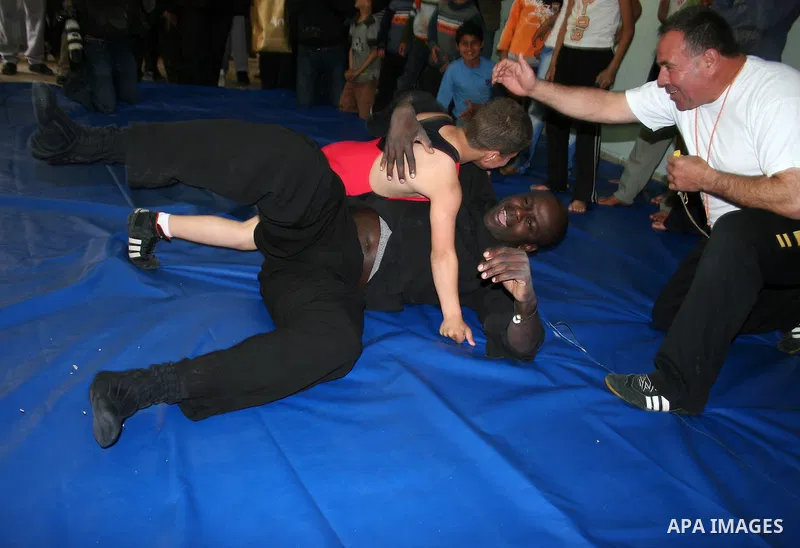 Former French football player Lilian Thuram plays with a Palestinian boy and a referee following a wrestling game at the Tareq Ben Ziad Club in the West Bank city of Hebron on April 13, 2011. Thuram is visiting the Pales...