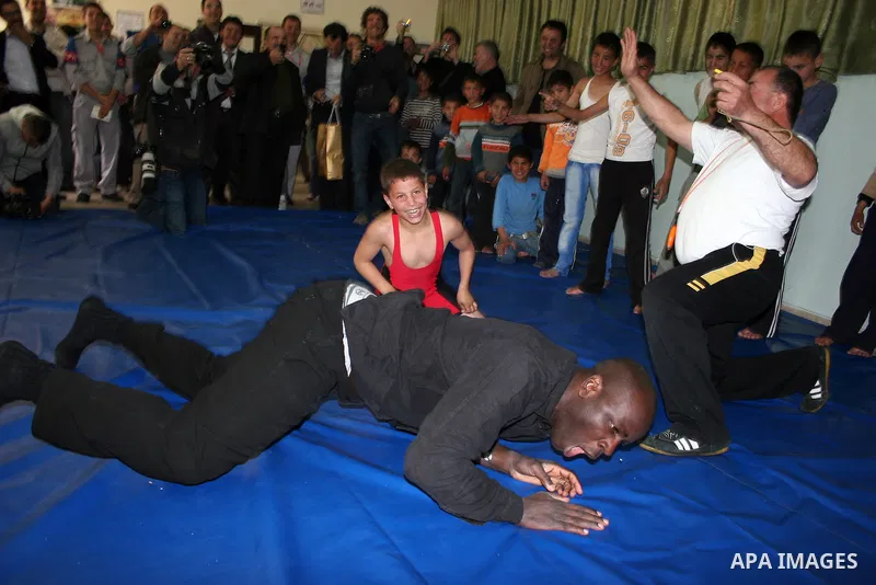 Former French football player Lilian Thuram plays with a Palestinian boy and a referee following a wrestling game at the Tareq Ben Ziad Club in the West Bank city of Hebron on April 13, 2011. Thuram is visiting the Pales...