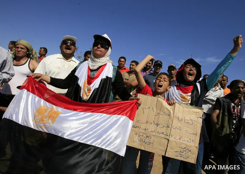 Egyptian protesters shout slogans and wave the national flag outside the Sharm el Sheikh International Hospital where the ousted Egyptian leader Hosni Mubarak was admitted after suffering medical complications during que...